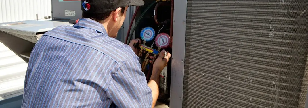 HVAC technician servicing a condenser unit in Brookings